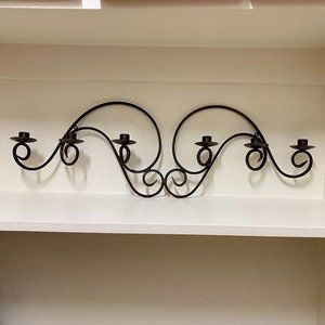 Wall mounted wrought iron candelabra for taper candles.